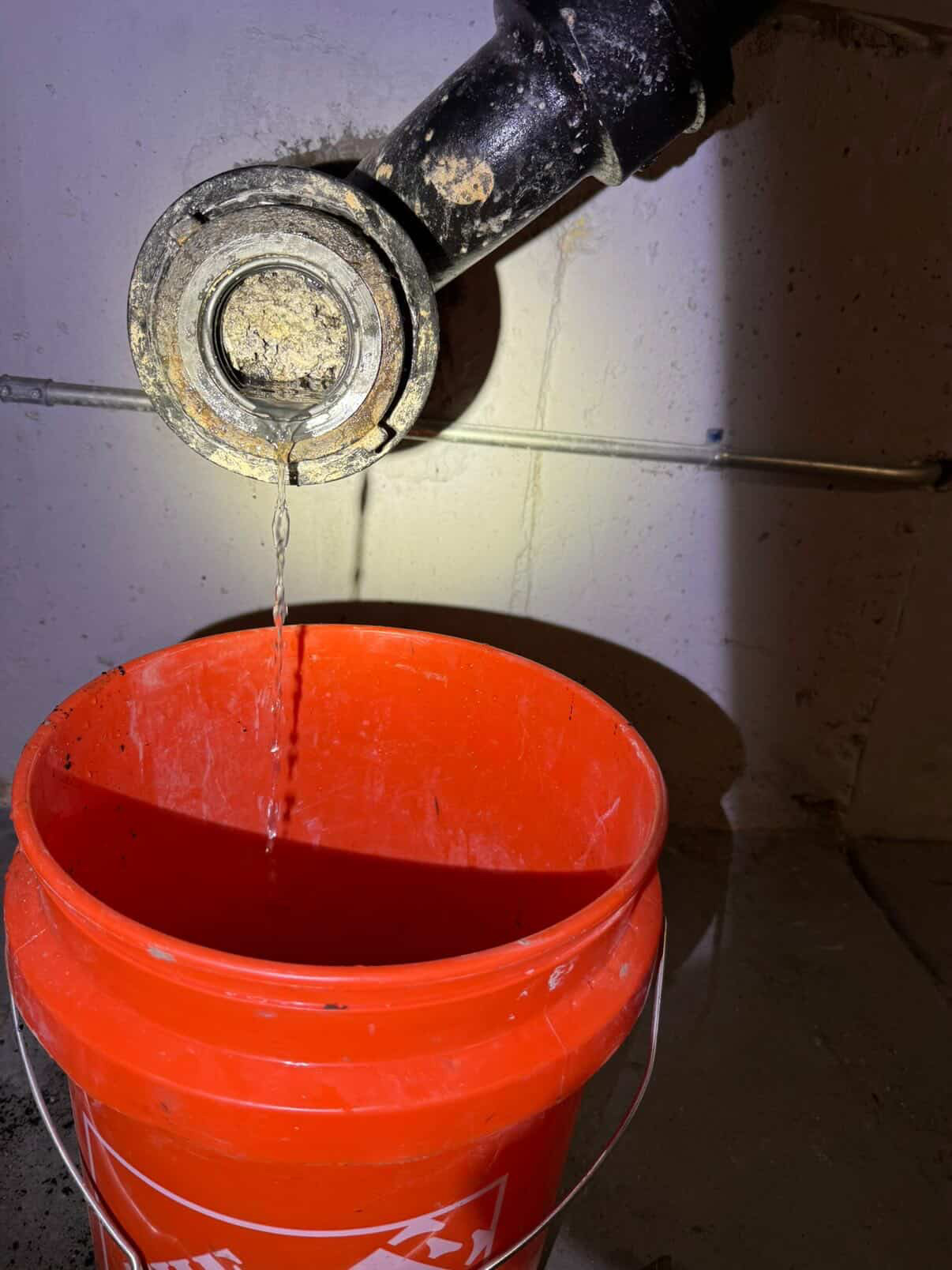 Cleared cast iron pipe draining into bucket after backup