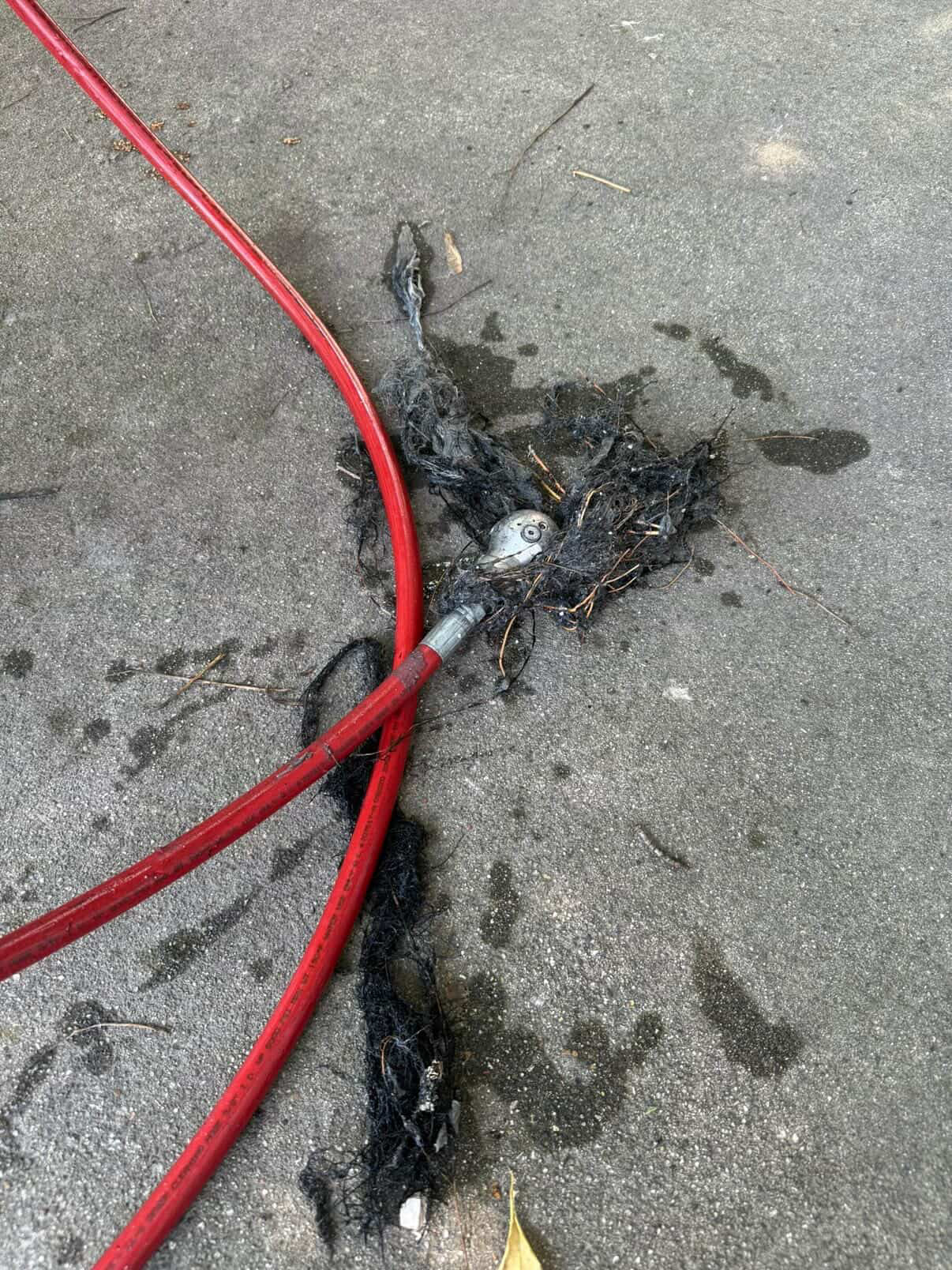 Hydro jet hose pulling sludge from a residential drain