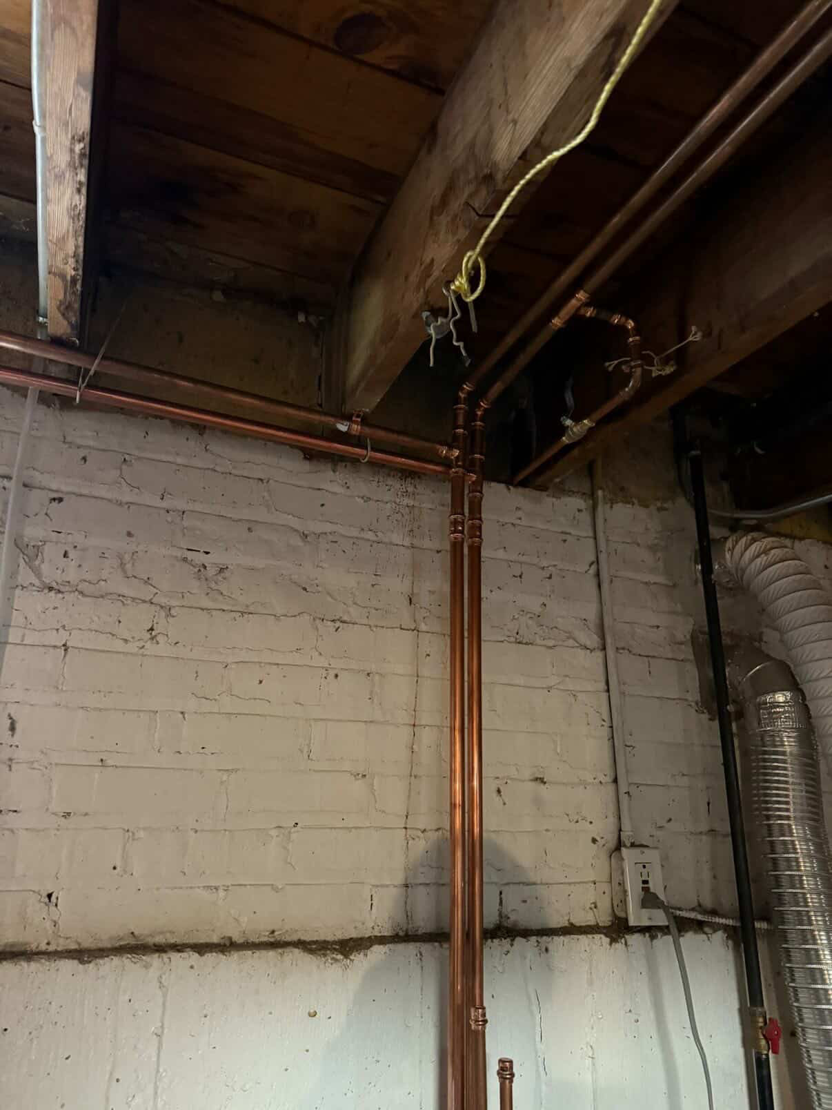 Clean copper repipe along a basement wall and ceiling